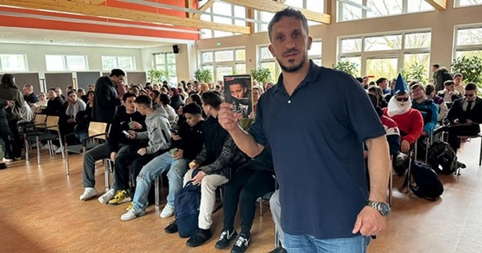 Fadi Saad mit seinem Buch bei einer Lesung vor Schülerinnen und Schülern