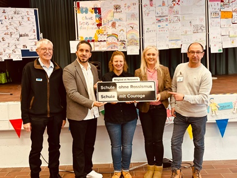 Fadi Saad bei der Schule am Gutspark mit dem Schild „Schule ohne Rassismus – Schule mit Courage“